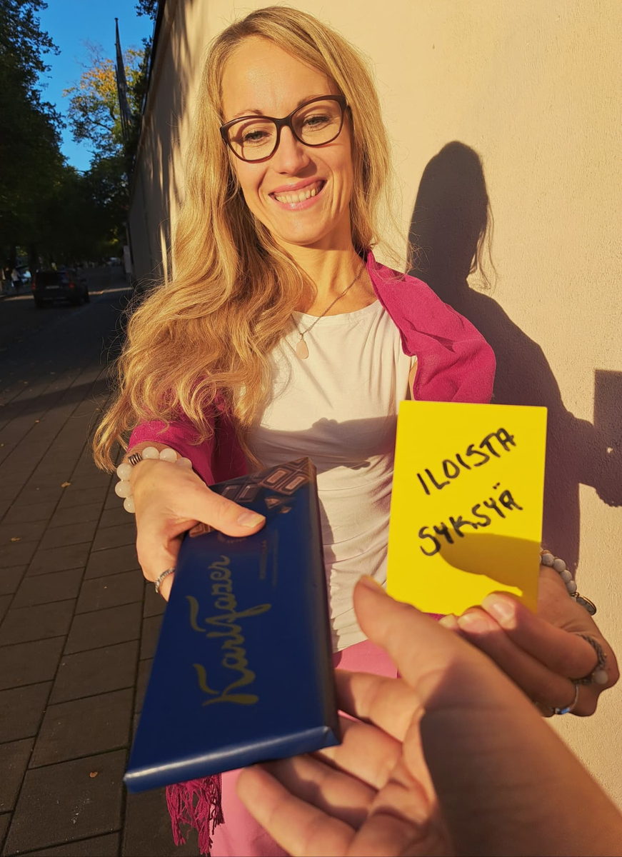 Nainen ojentaa suklaapatukan ja keltaisen kortin